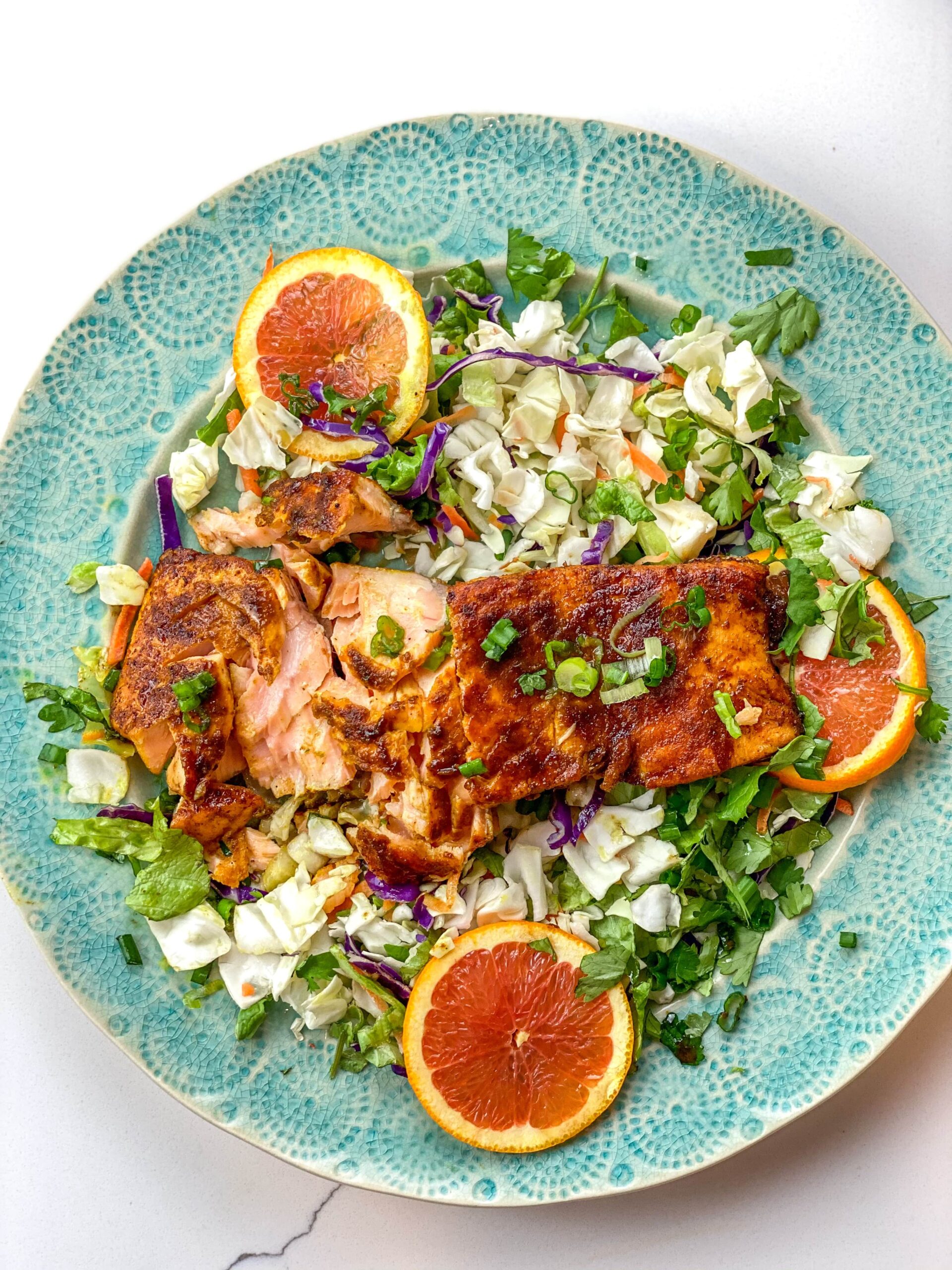 a plate of turmeric salmon with a grapefruit tamari glaze and cabbage salad