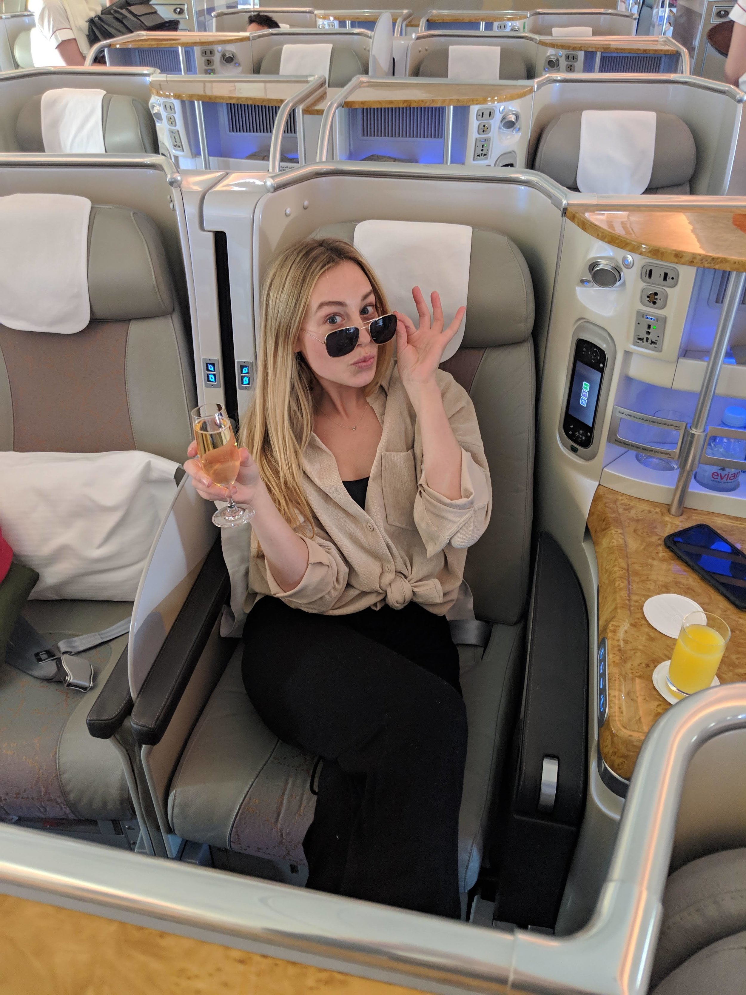 woman in Emirates business class with champagne