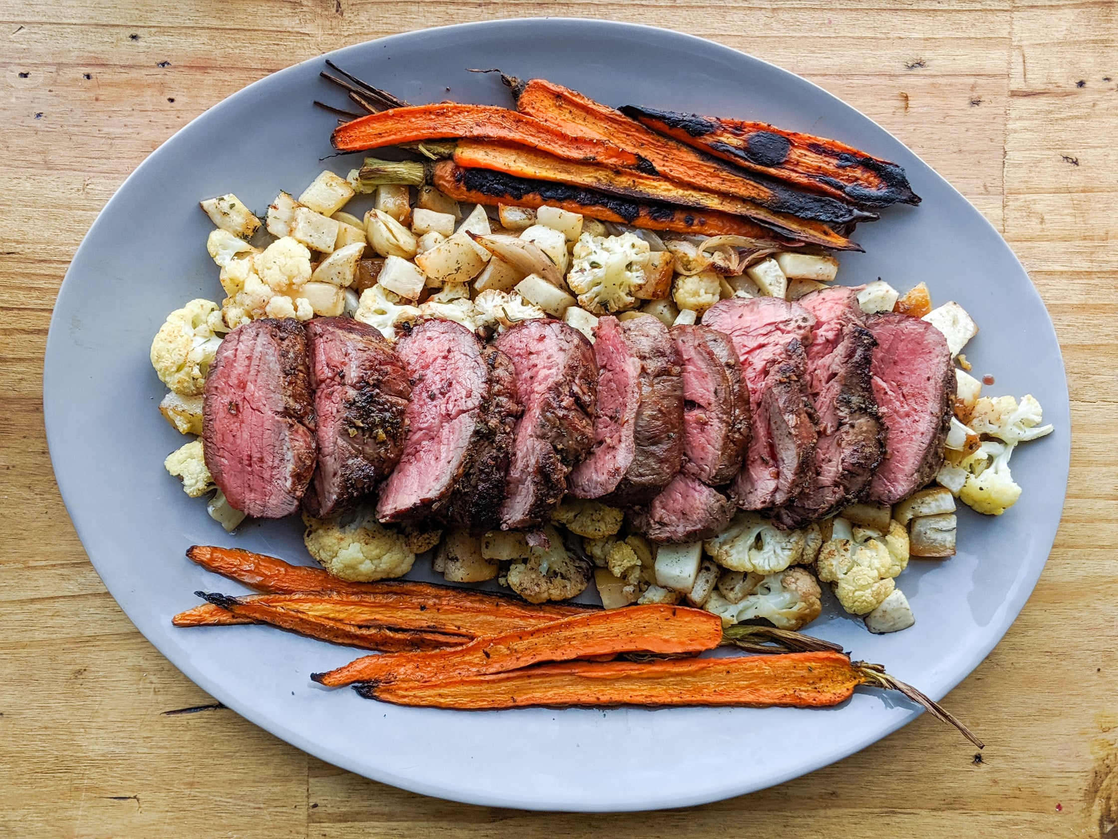 a platter of beef tenderloin and roasted veggies